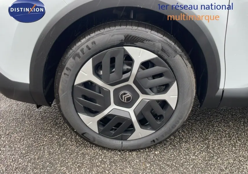 Gros plan sur la roue avant gauche d'une Citroën C4 blanc métal, mettant en valeur la jante au design moderne bicolore.