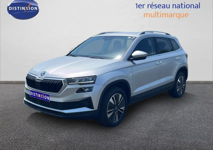 Vue 3/4 avant d’un Skoda Karoq 2025 gris argenté avec jantes bi-ton et calandre noire distinctive.