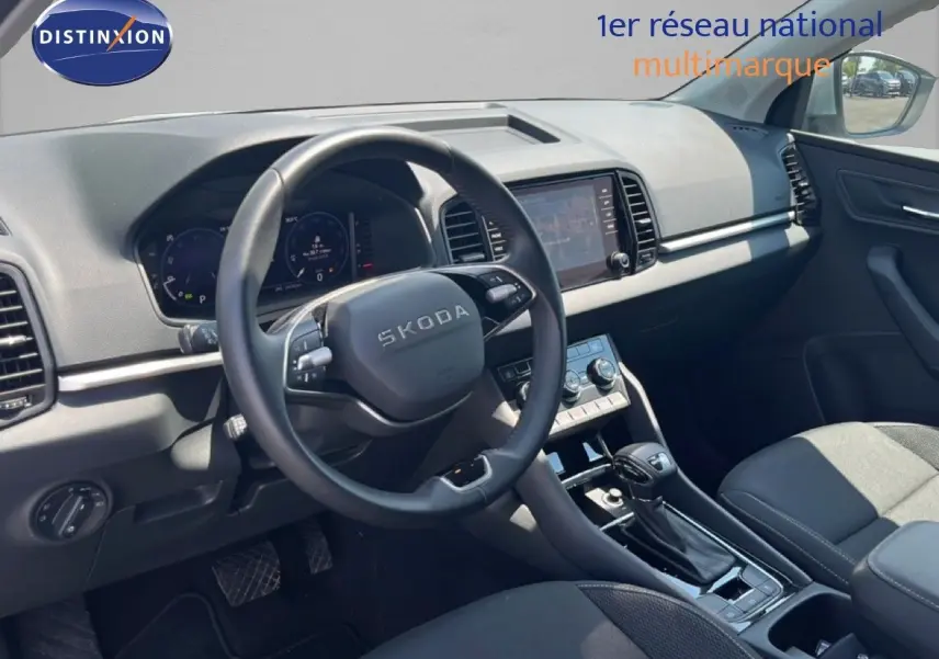 Vue intérieure côté conducteur du Skoda Karoq 2025, tableau de bord et volant noirs avec écran tactile central.