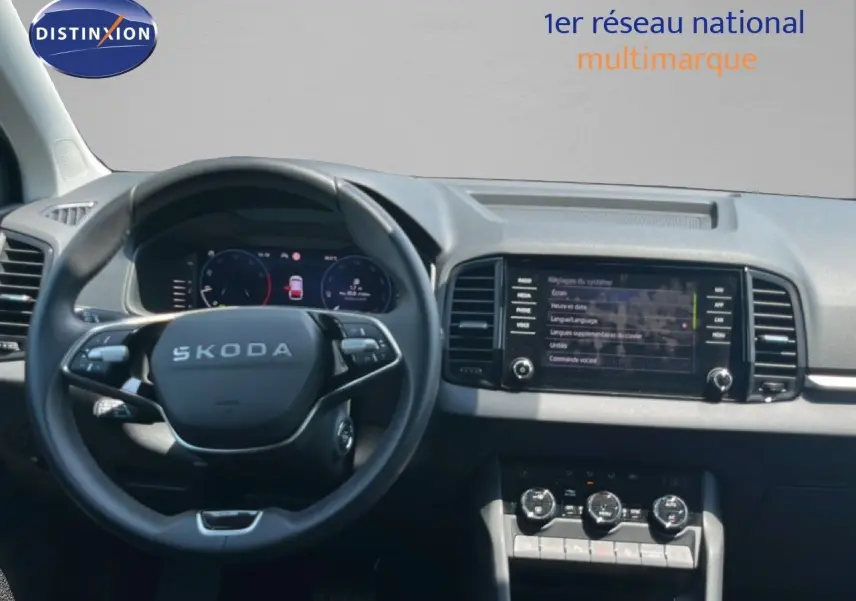 Vue intérieure centrée sur le volant SKODA et le tableau de bord avec écran tactile et commandes climatisation.