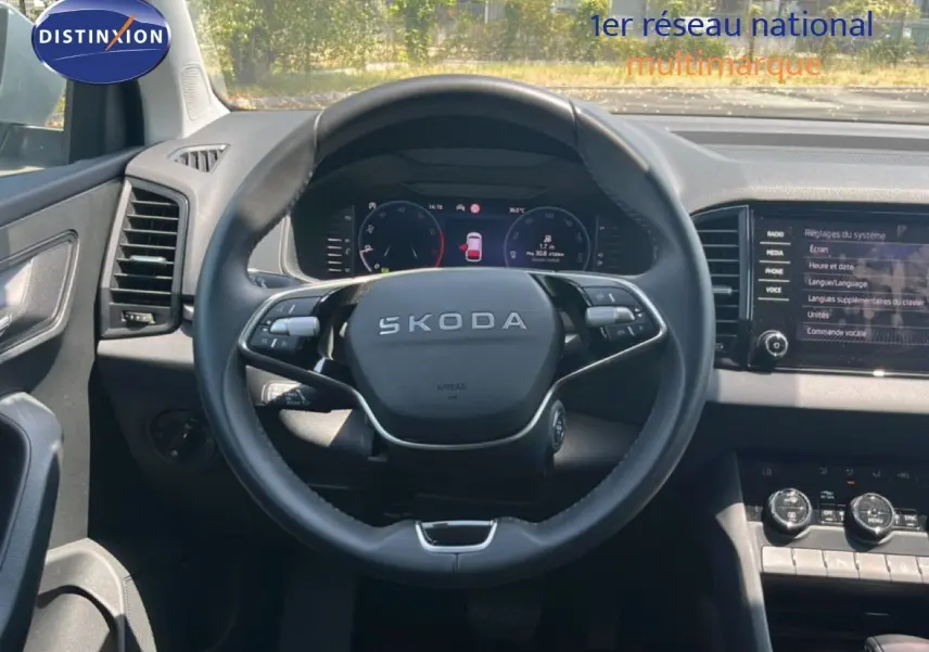 Vue intérieure centrée sur le volant SKODA d’un Karoq 2025, avec tableau de bord numérique et écran tactile gris noir.