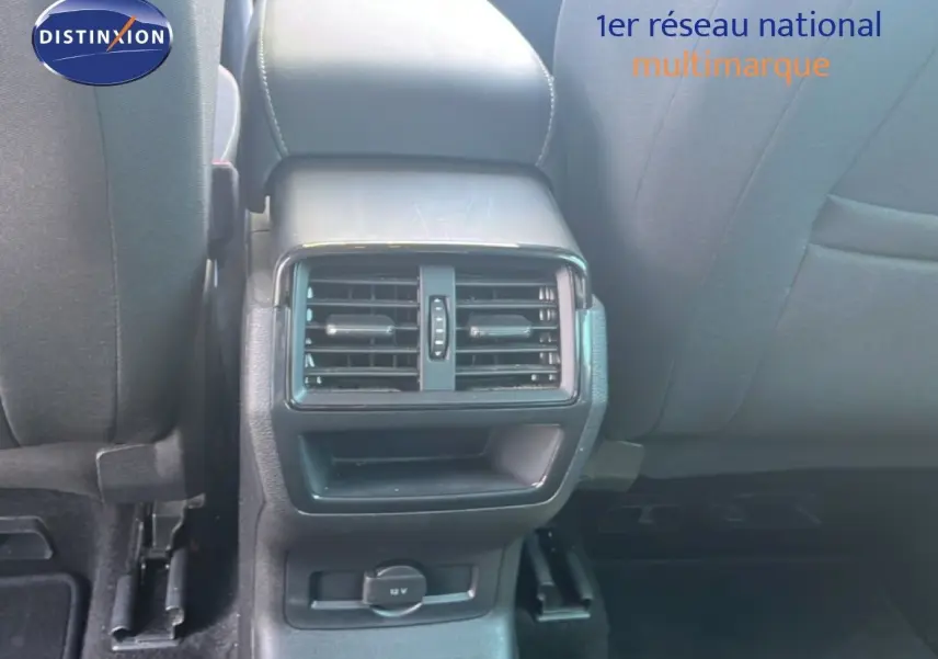 Vue rapprochée des aérateurs arrière et prise 12V sur la console centrale d’un Skoda Karoq gris intérieur tissu noir.
