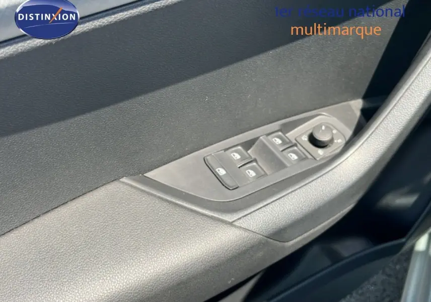 Gros plan sur la commande des vitres électriques côté gauche de la porte d’une Skoda Karoq 1.5 TSI 2025 couleur argent.
