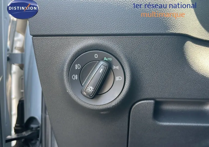 Gros plan sur la molette de commande des phares dans l'habitacle gris noir du Skoda Karoq Reflex Silver.