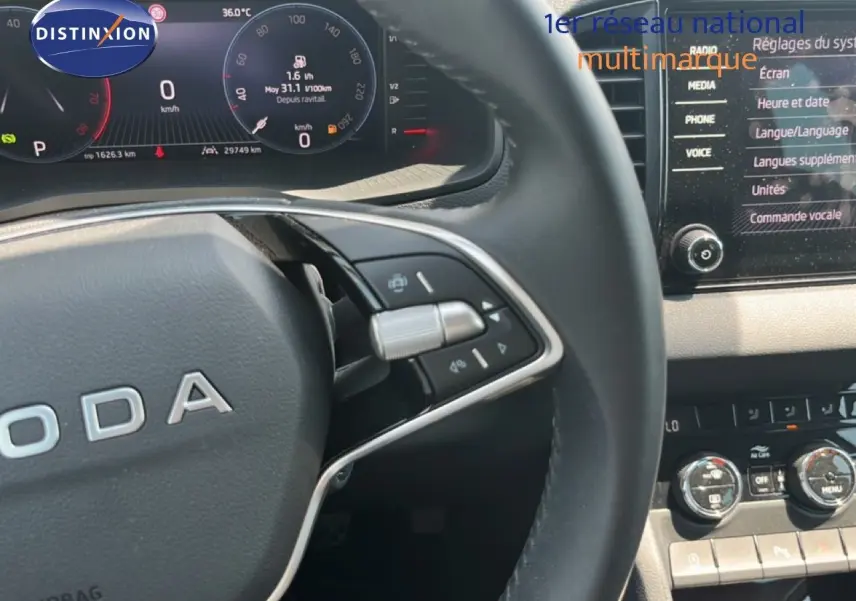 Gros plan sur le volant et le tableau de bord numérique d’un Skoda Karoq 2025, finition Selection, intérieur gris noir.