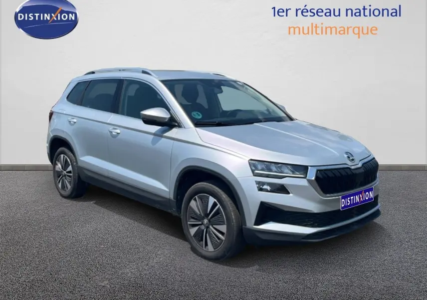 Vue 3/4 avant d’un Skoda Karoq 2025 en Reflex Silver Metal avec calandre noire et jantes bi-ton.