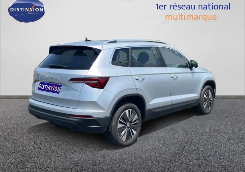 Vue 3/4 arrière droite d'un Skoda Karoq 2025 en Reflex Silver Metal avec jantes bi-ton et vitres teintées.