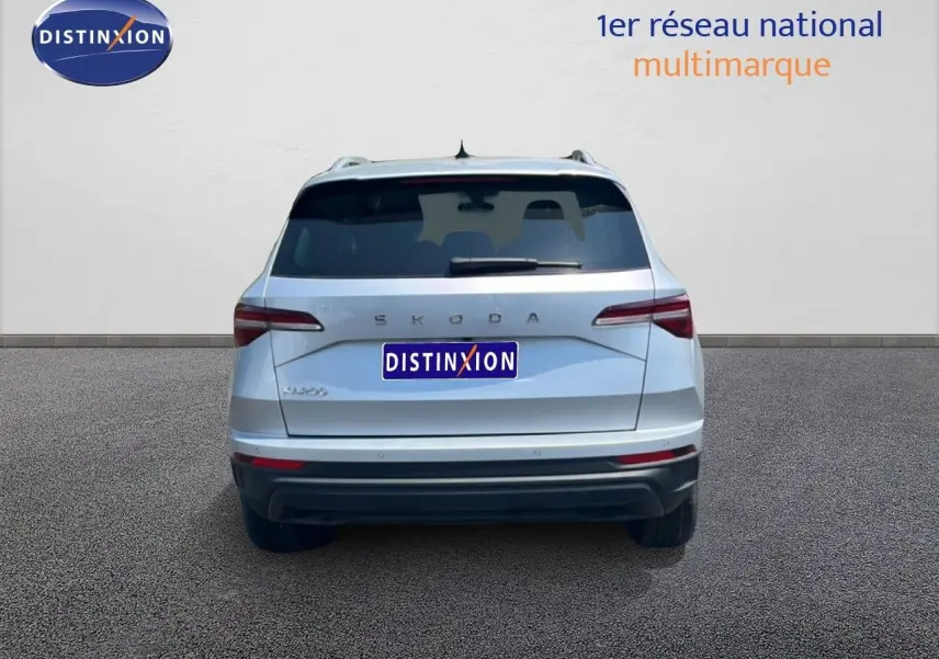 Vue arrière d'un Skoda Karoq 2025 en argent Reflex Silver Metal, avec feux arrière LED et logo distinctif.