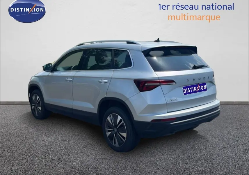 Vue 3/4 arrière droite d’un Skoda Karoq 2025 en Reflex Silver Metal avec feux arrière LED et jantes bi-ton.