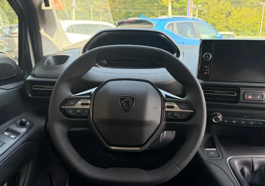 Vue intérieure centrée sur le volant cuir multifonctions du Peugeot Partner blanc, avec tableau de bord et écran tactile visibles.