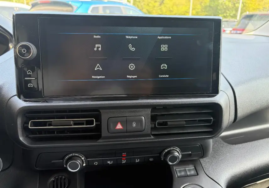 Vue rapprochée de l’écran tactile central et de la console de climatisation du Peugeot Partner blanc, version 2026.