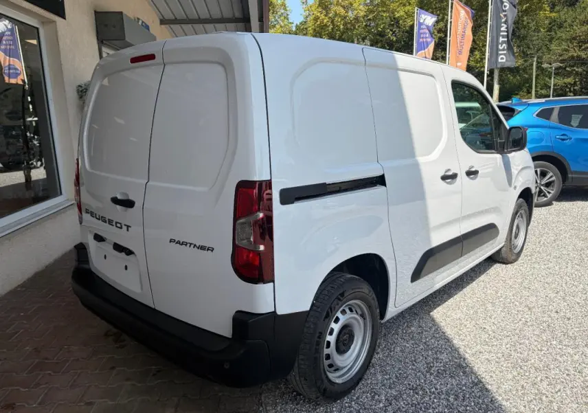Vue 3/4 arrière droite du Peugeot Partner blanc, fourgon utilitaire avec portes arrière battantes et protections noires.