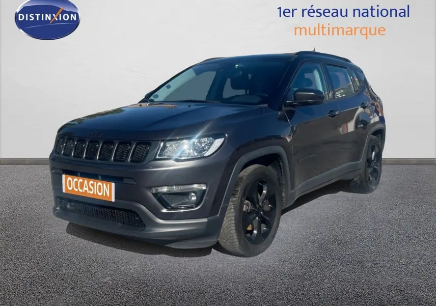 Jeep Compass gris foncé en 3/4 avant droit, version Brooklyn Edition avec jantes noires et calandre distinctive.