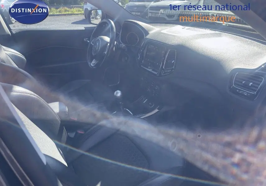 Vue intérieure côté conducteur du Jeep Compass 2019, montrant le volant, la console centrale et la boîte manuelle.