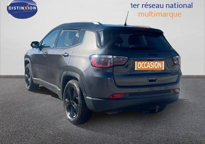 Vue 3/4 arrière droite d'un Jeep Compass gris foncé Brooklyn Edition, roues noires et plaque "Occasion" visible.