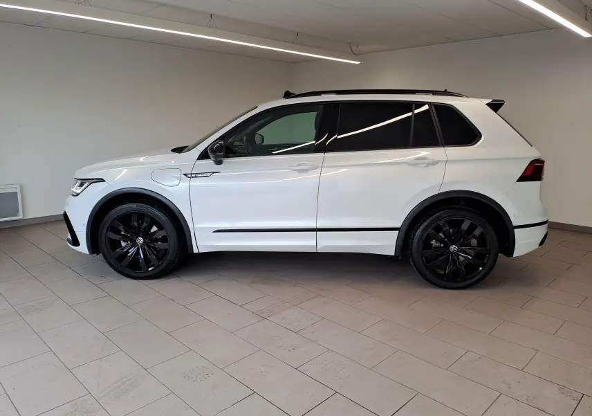 Vue de profil côté gauche du Volkswagen Tiguan 1.4 eHybrid blanc nacré avec jantes noires 20 pouces Suzuka et attelage escamotable.