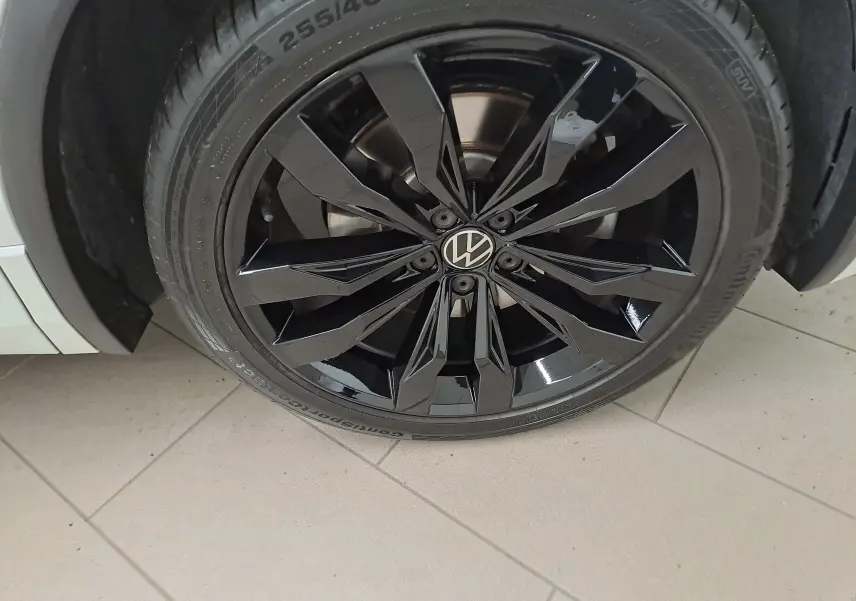 Gros plan sur la jante noire 20 pouces Suzuka du côté avant droit du Volkswagen Tiguan blanc nacré 2023.