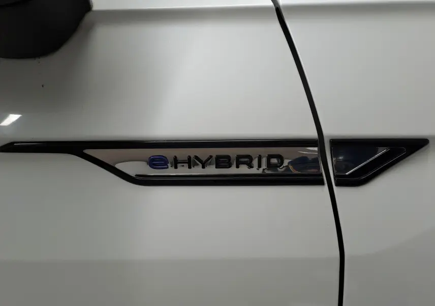 Détail du badge eHybrid sur la portière blanche nacrée d'un Volkswagen Tiguan 2023, version hybride rechargeable.