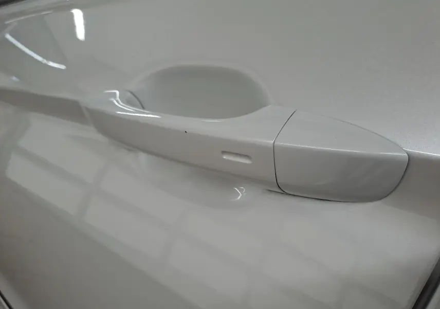 Poignée de porte côté gauche du Volkswagen Tiguan 1.4 eHybrid blanc nacré, vue rapprochée sur la finition lisse.