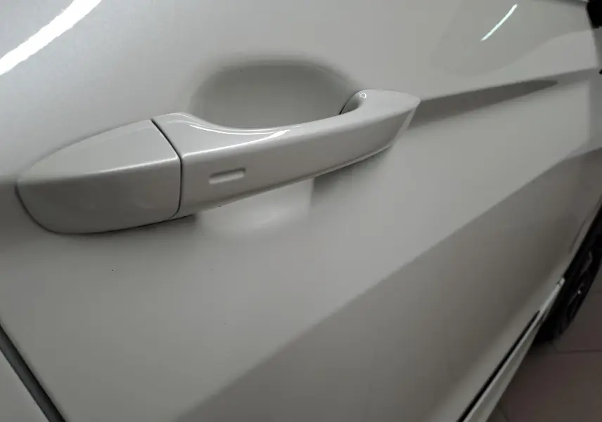 Poignée de porte côté gauche en gros plan sur Volkswagen Tiguan blanc nacré 2023 avec peinture nacrée Oryx.