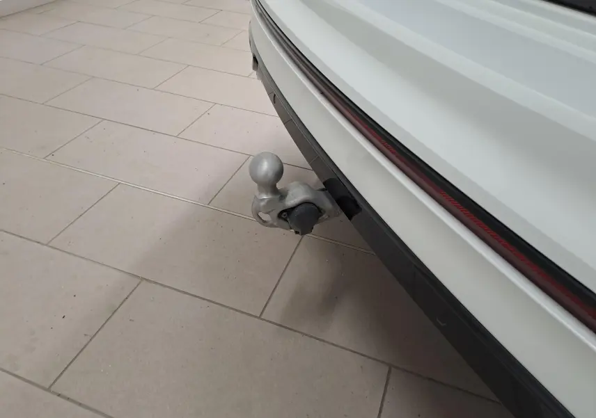 Gros plan sur le crochet d'attelage escamotable arrière d'un Volkswagen Tiguan blanc nacré, version 2023.