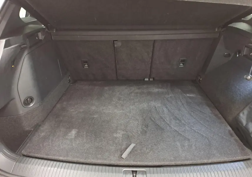 Coffre ouvert du Volkswagen Tiguan 1.4 eHybrid 2023, vue intérieure, tapis de sol gris et garnitures noires.