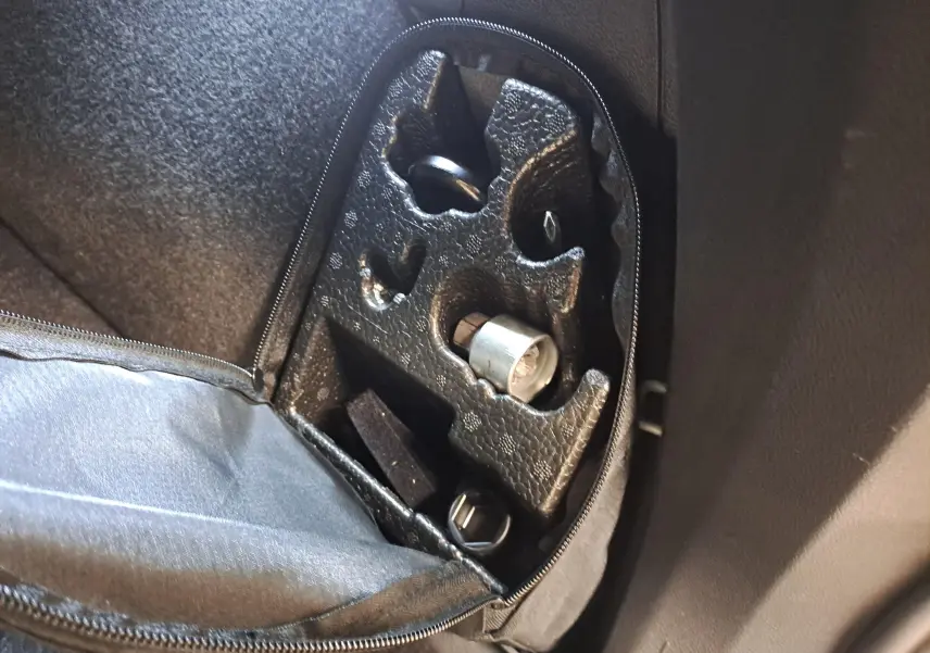 Gros plan sur la trousse à outils dans le coffre du Volkswagen Tiguan blanc nacré 2023 hybride rechargeable.