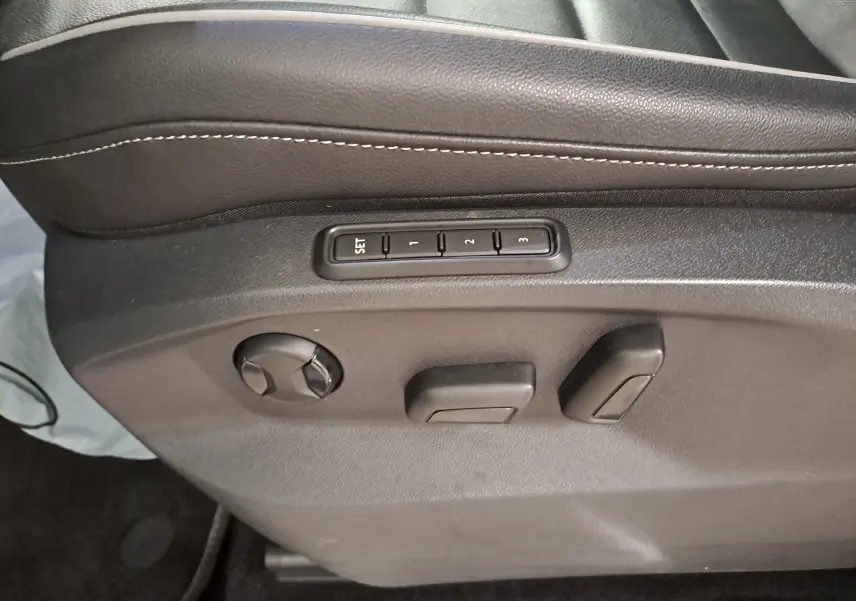 Détail des commandes de réglage électrique du siège conducteur noir du Volkswagen Tiguan blanc nacré 2023.