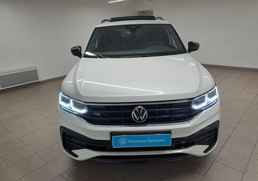 Vue de face du Volkswagen Tiguan blanc nacré 2023 avec feux LED allumés et calandre R-Line distinctive.