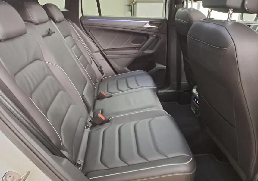 Vue intérieure côté gauche des sièges arrière en cuir noir avec surpiqûres blanches du Volkswagen Tiguan blanc nacré 2023.