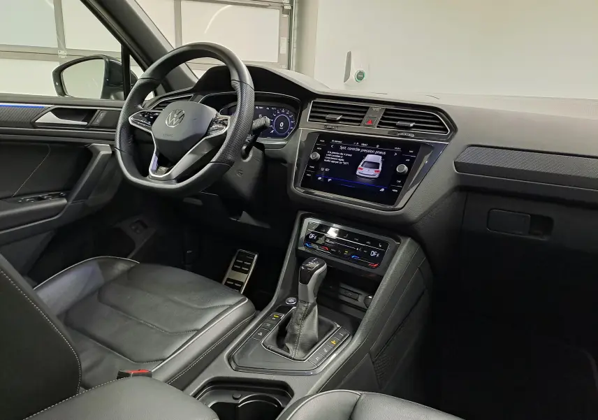 Vue intérieure côté conducteur du Volkswagen Tiguan 2023, tableau de bord et console centrale avec écran tactile et levier de vitesse.