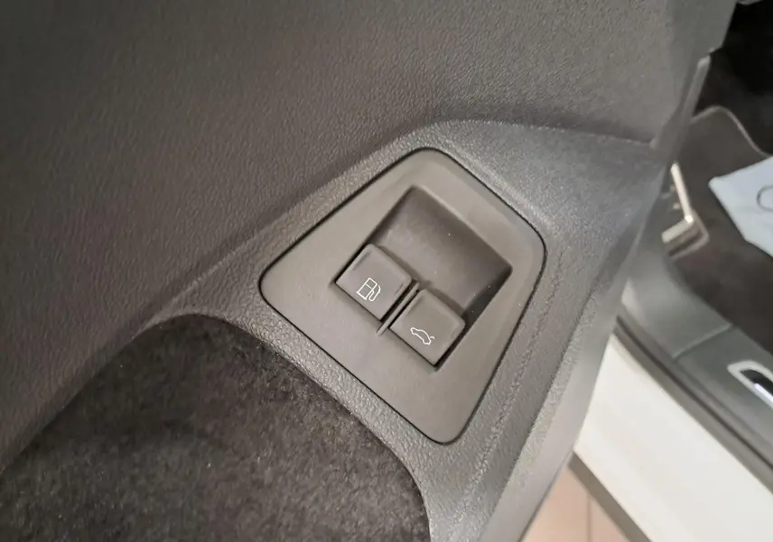 Boutons d'ouverture du coffre et de la trappe à carburant sur le côté gauche intérieur d'un Volkswagen Tiguan blanc nacré.