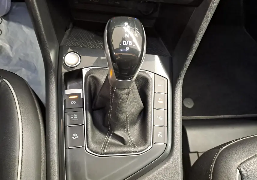 Gros plan sur la console centrale du Volkswagen Tiguan 1.4 eHybrid 2023 avec levier de vitesses et boutons de contrôle.