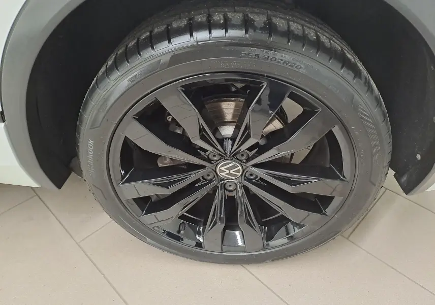 Gros plan sur la jante noire en alliage 20'' Suzuka du Volkswagen Tiguan blanc nacré, pneu 255/40 R20 visible.