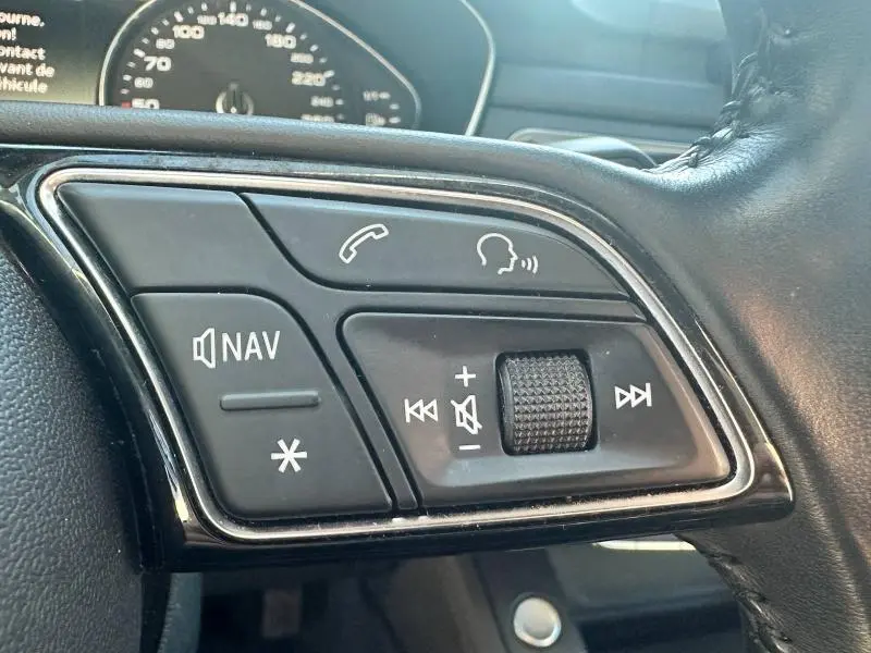 Gros plan sur les commandes audio et navigation au volant cuir noir de l’Audi A5 Sportback 2018.