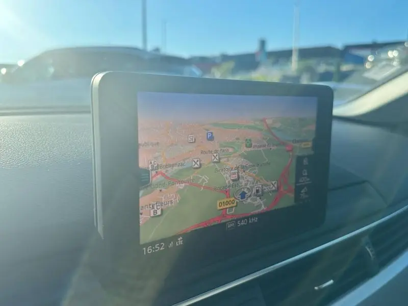 Écran GPS couleur en gros plan sur le tableau de bord de l'Audi A5 Sportback 2.0 TDI, lumière naturelle extérieure.