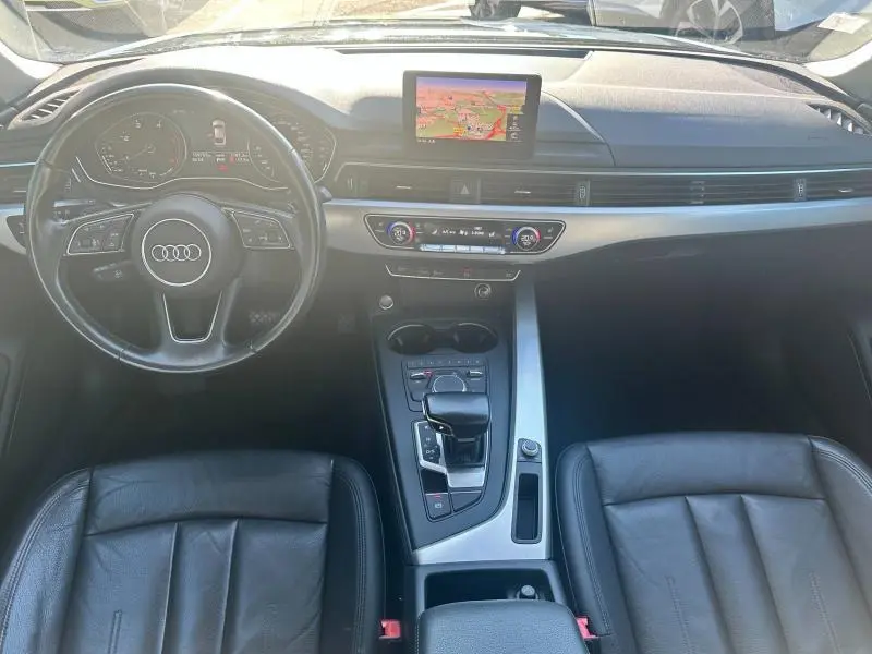Vue intérieure avant de l'Audi A5 Sportback 2018, tableau de bord noir avec écran GPS central et volant cuir multifonction.