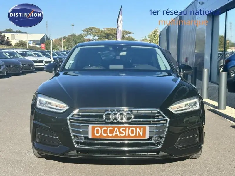 Vue de face d'une Audi A5 Sportback noire avec calandre chromée et plaques "OCCASION" en orange.