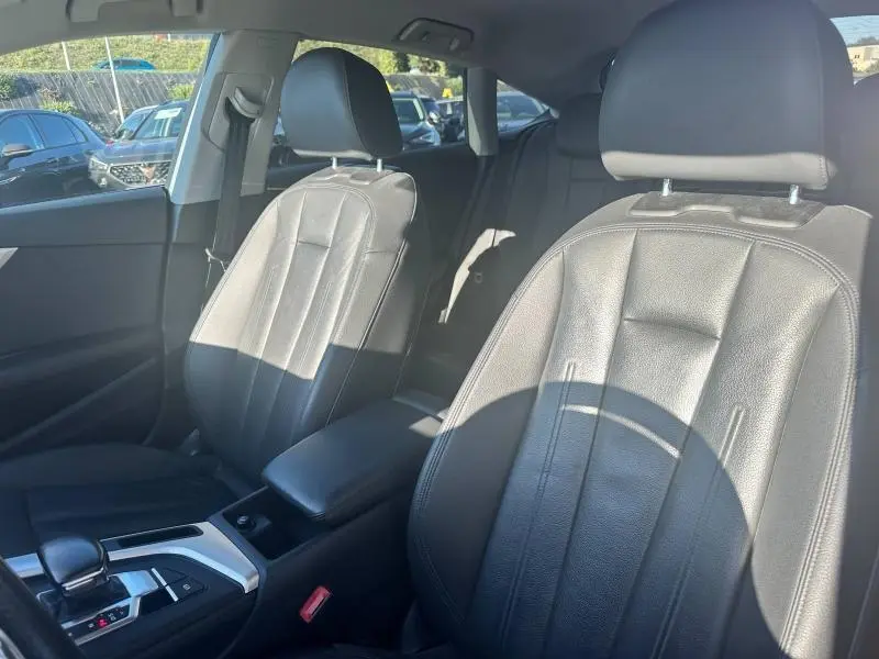 Vue intérieure côté avant droit de l'Audi A5 Sportback 2018, sièges en cuir noir et accoudoir central.