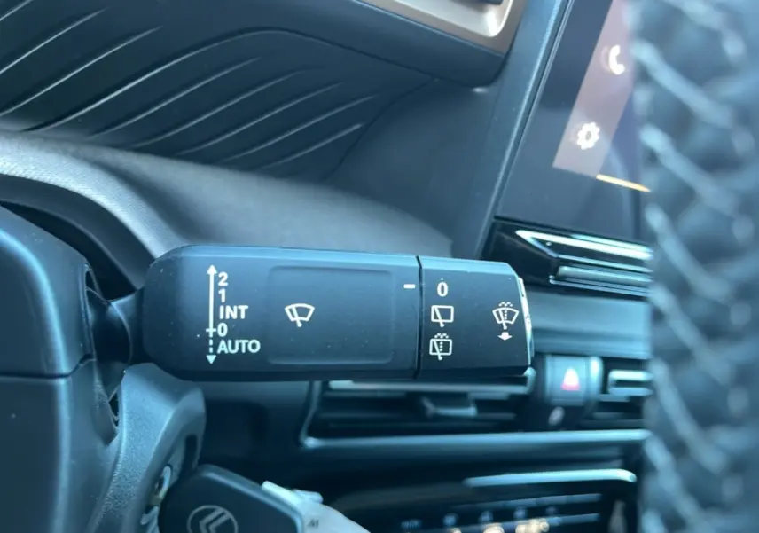Gros plan sur la commande des essuie-glaces à gauche du volant dans l’habitacle noir du Citroën C3 Aircross 2025.