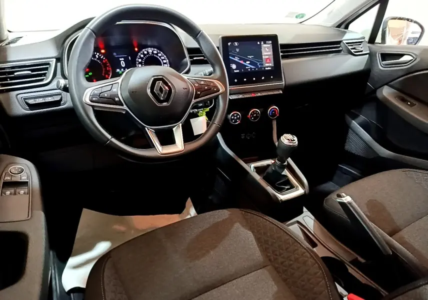 Vue intérieure côté conducteur de la Renault Clio Business 2021, volant cuir, écran tactile et levier de vitesses manuel visibles.