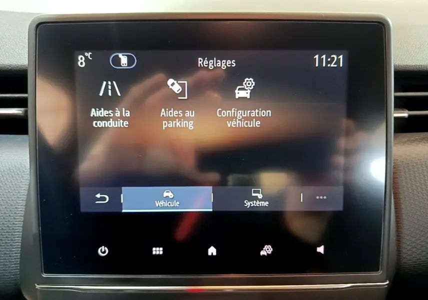 Écran tactile central de la Renault Clio Business blanc, affichant les réglages d’aides à la conduite et parking.
