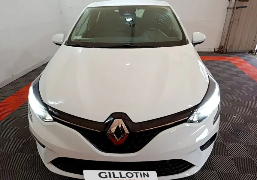 Vue avant d'une Renault Clio Business blanche avec phares LED allumés dans un garage fermé.