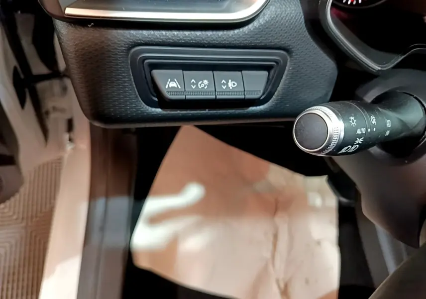 Vue rapprochée de la commande des aides à la conduite et du commodo d’éclairage dans une Renault Clio Business blanche.