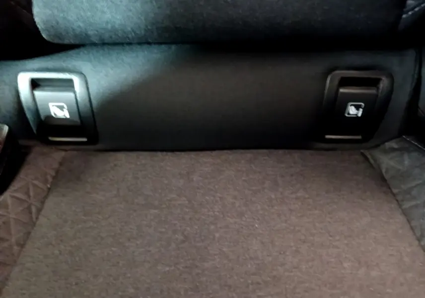 Gros plan sur les commandes de rabattement des sièges arrière dans l’habitacle noir de la Renault Clio Business blanche 2021.