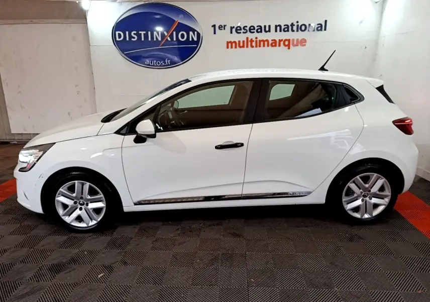 Profil droit d'une Renault Clio Business blanche 2021, avec jantes alliage et vitres teintées, en intérieur showroom.