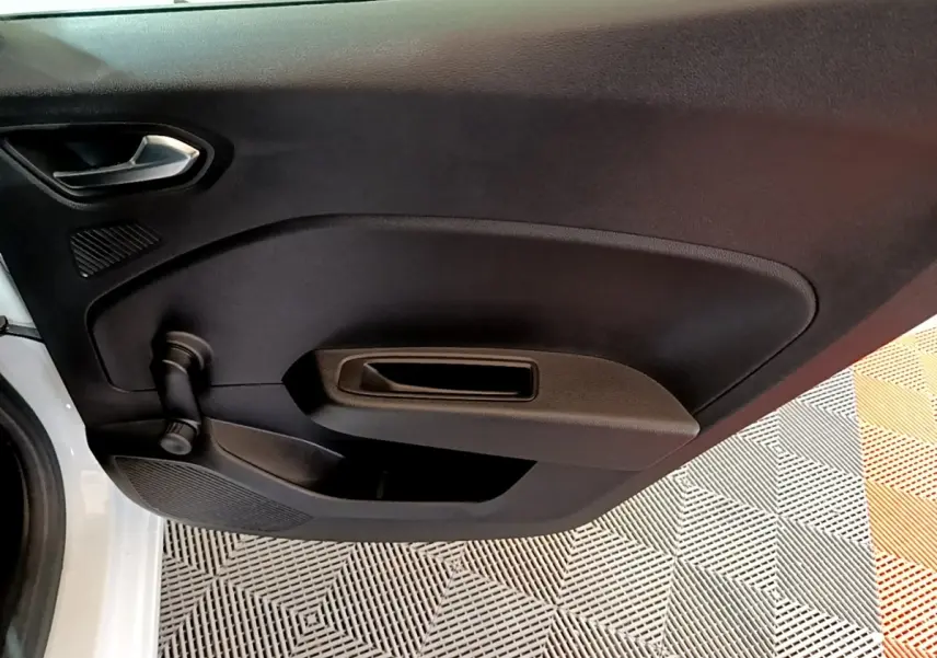 Vue rapprochée de la porte avant gauche noire d’une Renault Clio Business blanche, avec poignée intérieure et manivelle de vitre.