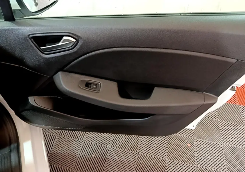 Vue intérieure côté gauche de la porte avant d’une Renault Clio Business blanche avec commande de vitre électrique.