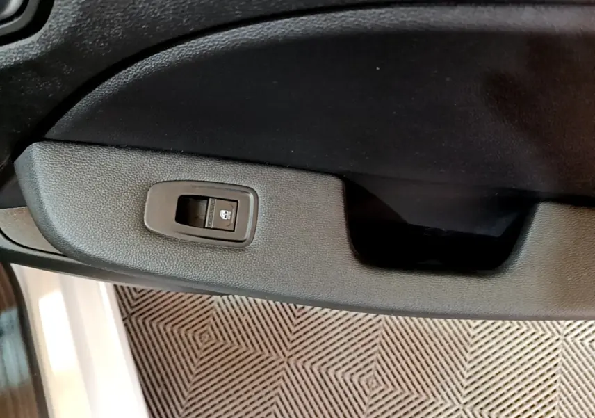 Gros plan sur la commande de verrouillage de porte côté intérieur d’une Renault Clio Business blanche, 2021.