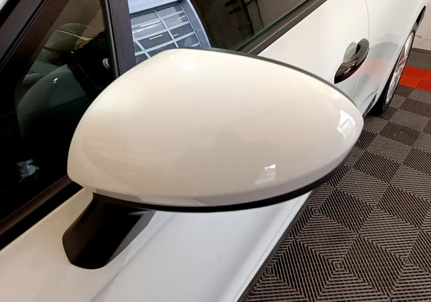 Rétroviseur côté gauche blanc de la Renault Clio Business 2021, avec porte et poignée visibles en arrière-plan.